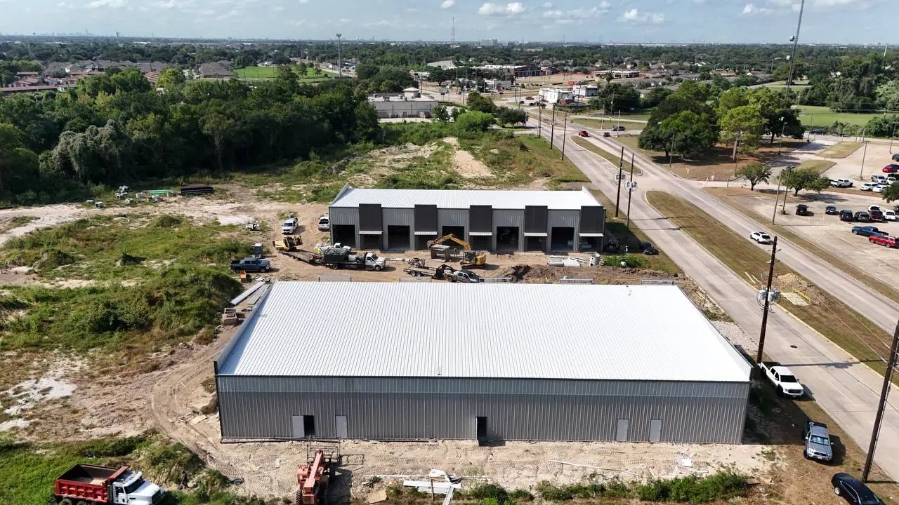 Bammel Business Park Phase 1 aerial drone photo, 27 August 2026 (Day 179): both flex warehouse buildings enclosed — the front building's grade-level drive-in bays and storefront openings are framed out, the rear building is fully clad with its standing-seam roof complete, 12902 Bammel N Houston Rd, Houston TX 77066