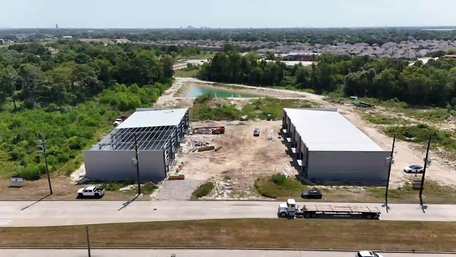 Bammel Business Park Phase 1 aerial drone photo, August 2026: right building fully clad with finished roof, left building steel-framed with panels being installed, both flex warehouse buildings on 5.33 acres at 12902 Bammel N Houston Rd, Houston TX 77066